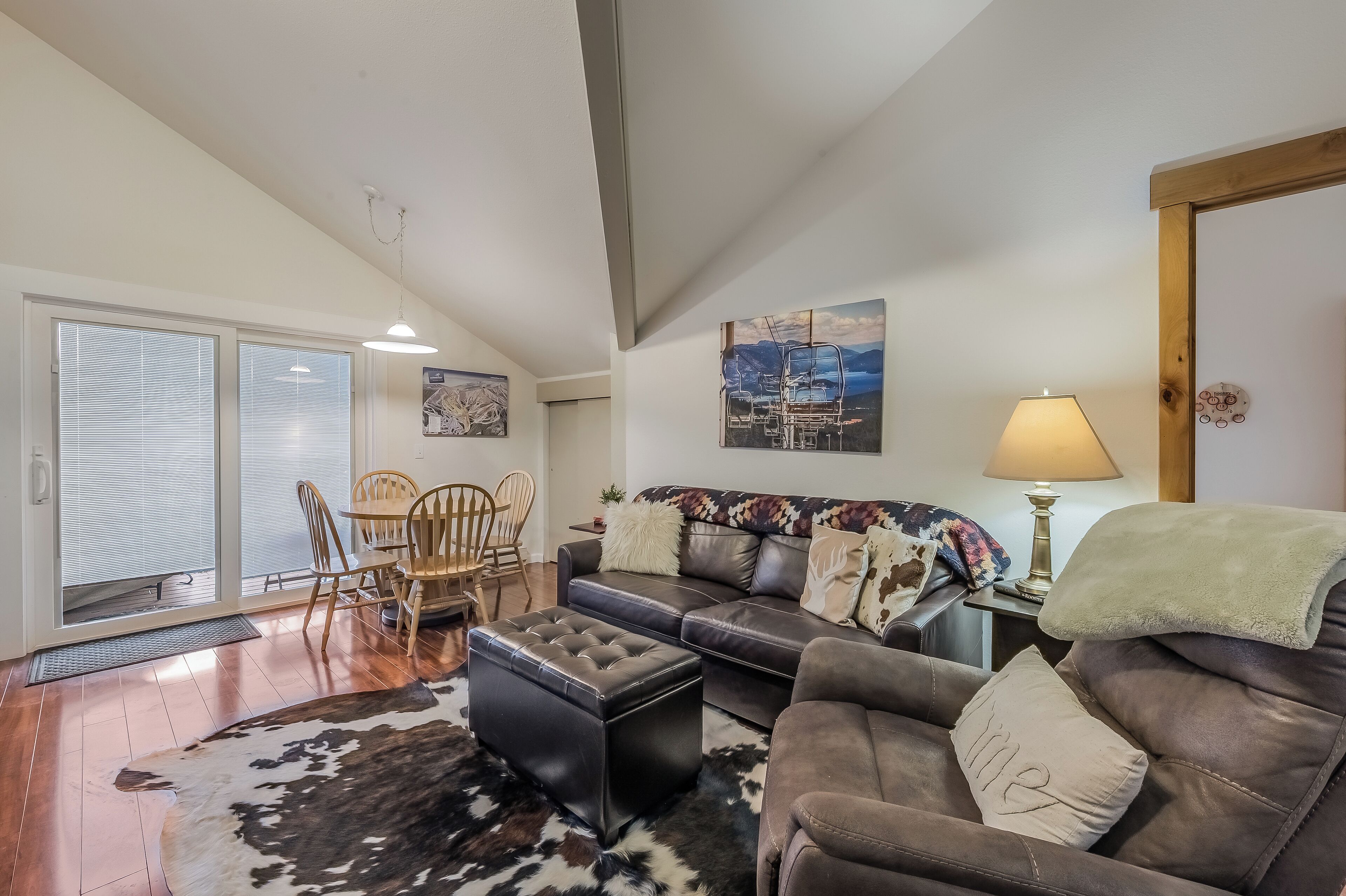 A spacious living room with a large sofa, a coffee table, and a dining area with chairs.