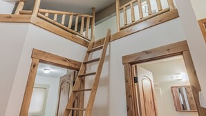 Eine Holztreppe mit Handlauf, die zu einer Zwischenebene im zweiten Stock führt.