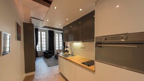 Une cuisine moderne dotée d’un four encastré, d’appareils électroménagers en acier inoxydable et d’un plan de travail en bois.