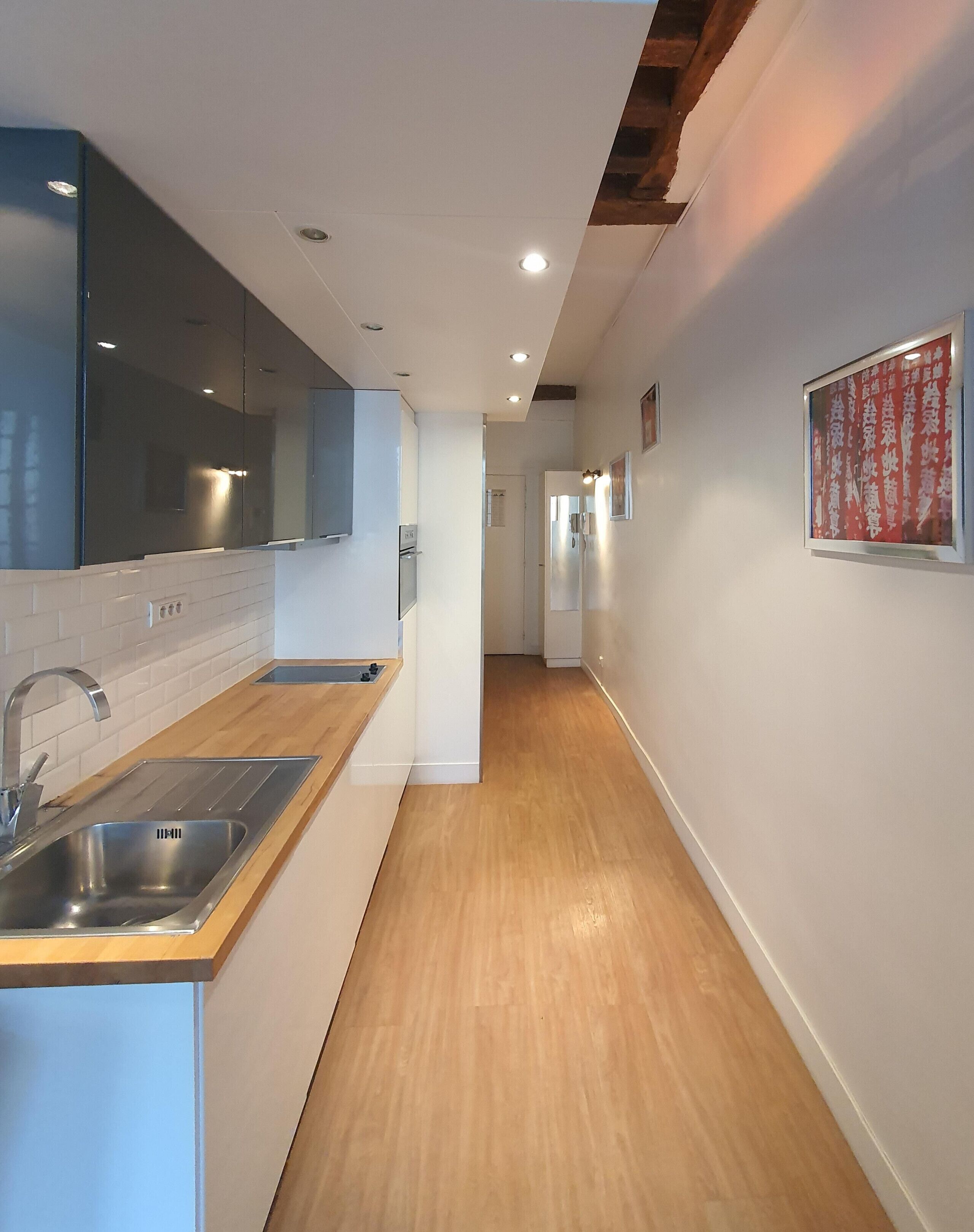 A modern kitchen with a wooden countertop, stainless steel sink, and a built-in oven.