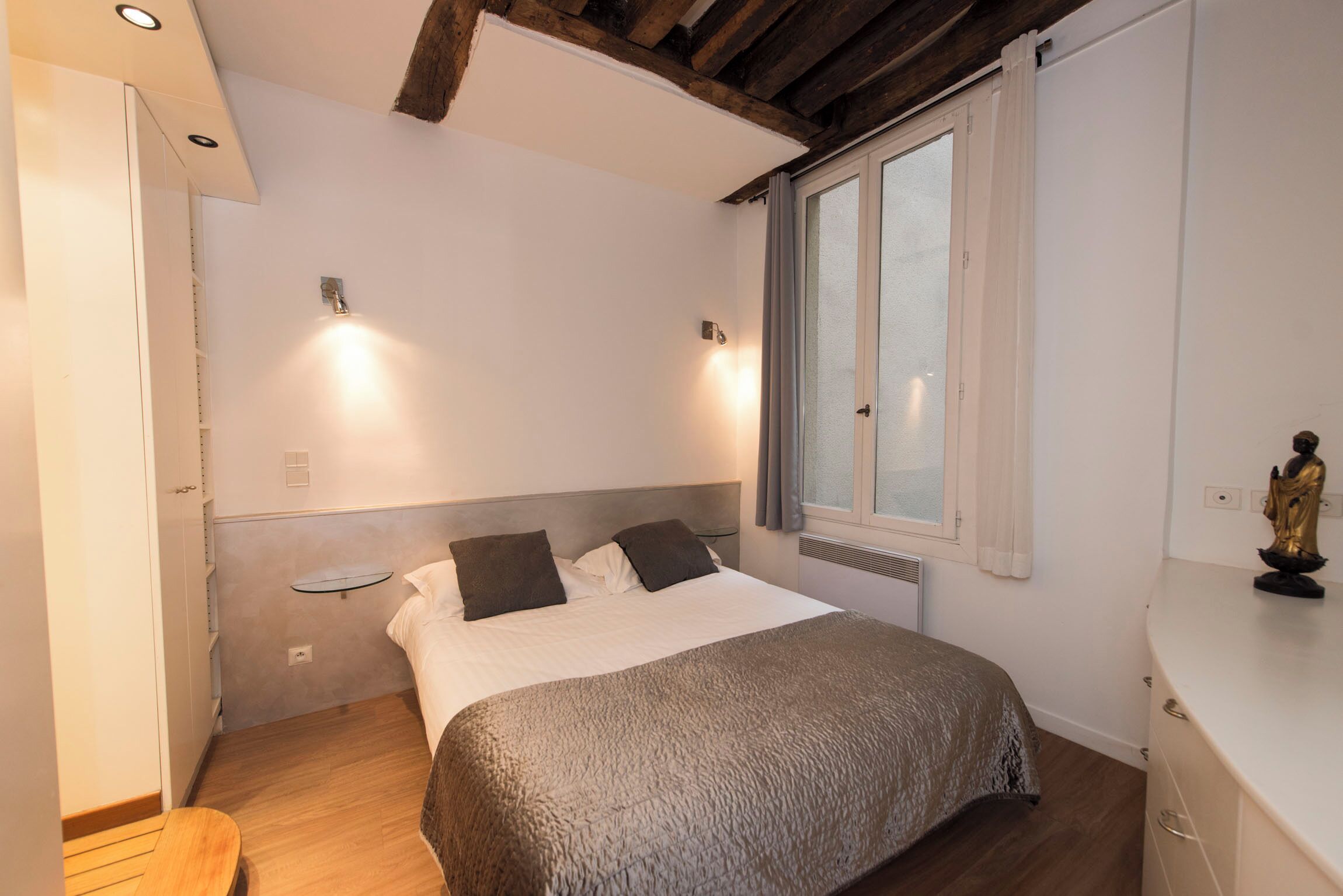 Ein Schlafzimmer mit Bett, Nachttisch und einem Fenster mit Vorhängen.