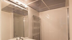 Une salle de bain moderne avec un lavabo blanc, un miroir et un porte-serviettes.