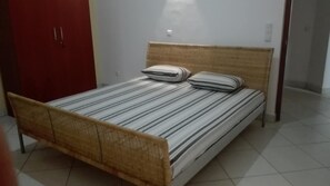 Cozy retreat with a single bed, striped mattress, and two pillows, set against a plain white wall.