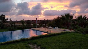 A swimming pool with a view of a sunset and clouds.