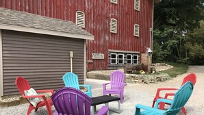 A gravel patio with colorful Adirondack chairs and a table in front of a red barn with a sign indicating a restaurant. - Surrounded by Salamonie State Park & Reservoir Newly Converted Barn! (Lagro)