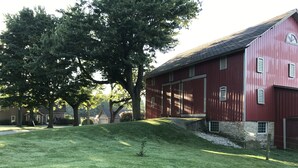 A red barn with a stone foundation and a grassy yard. - Surrounded by Salamonie State Park & Reservoir Newly Converted Barn! (Lagro)