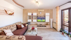 Un salon moderne comprenant un canapé, une table basse, un téléviseur et des objets de décoration.