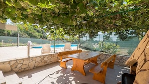 Une terrasse extérieure avec des murs en pierre, une piscine et une vue sur un plan d’eau.