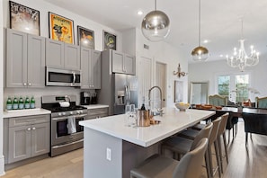 A modern kitchen with grey cabinets, stainless steel appliances, and a central island with bar seating.