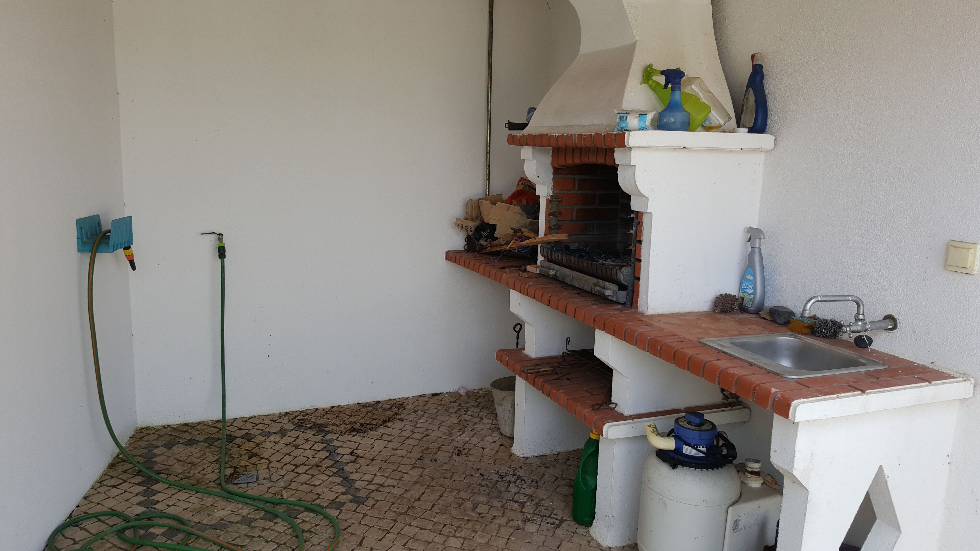 A kitchen with a sink, a gas stove, and a hose.