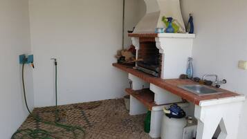 A kitchen with a sink, a gas stove, and a hose.