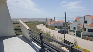 A balcony with a view of a residential street, houses, and distant hills. - Villa on Beach Azul Beach (Silveira)