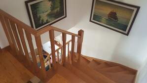 A wooden staircase with a handrail, leading to a landing with a bed and a bedside table. - Villa on Beach Azul Beach (Silveira)