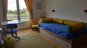 Un dormitorio con una cama, un escritorio, una silla y una ventana con cortinas.
