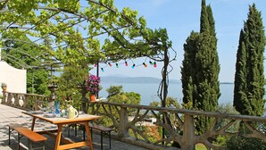 Un patio al aire libre con una mesa y bancos, con vistas a un cuerpo de agua y vegetación.