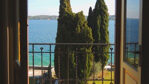 Un balcón con vista al mar, baranda de metal y piso de madera.