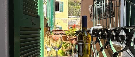 A balcony with a table, two wine glasses, and a bottle of wine.