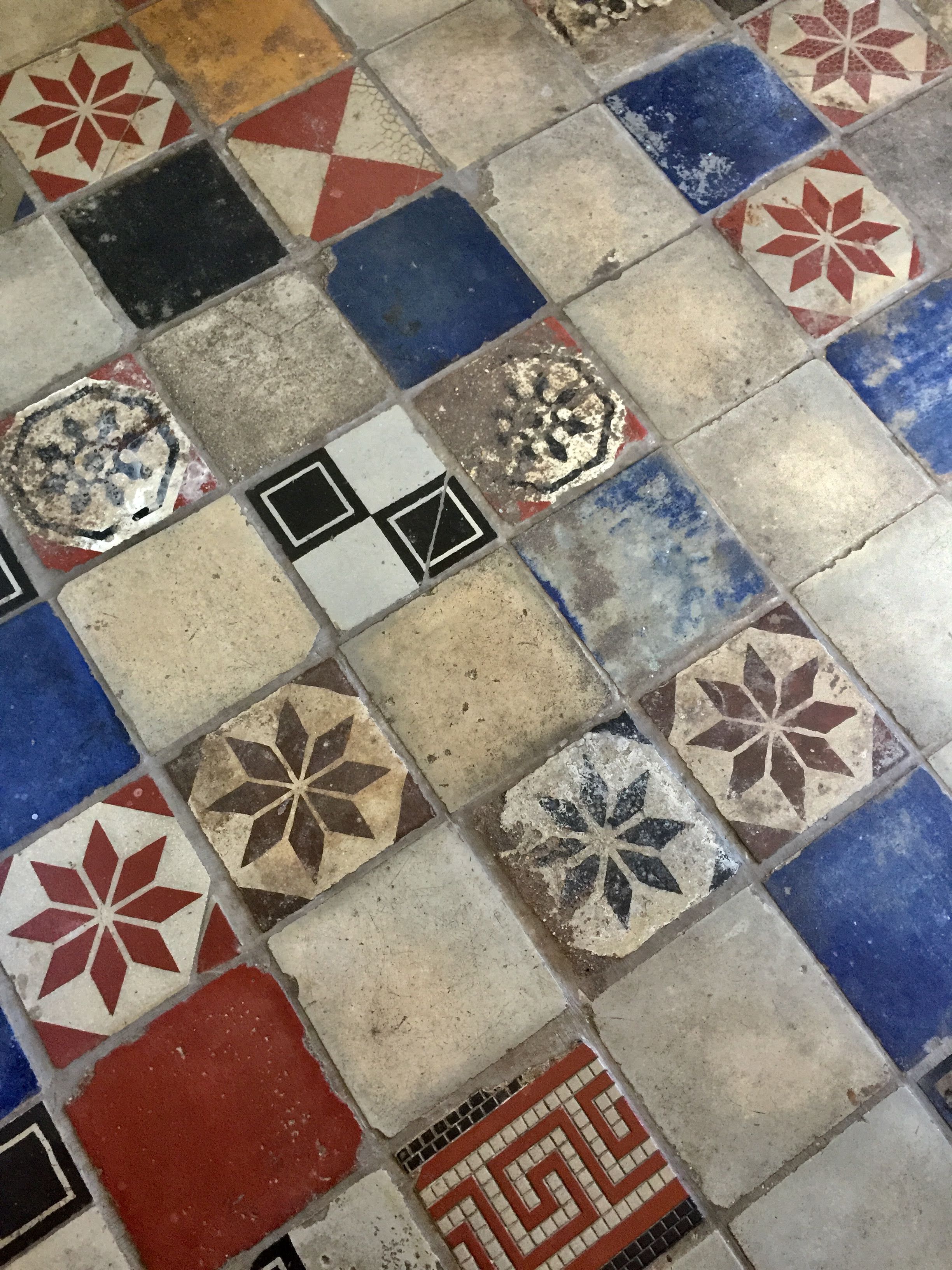 A close-up of a floor with variously colored and patterned tiles.