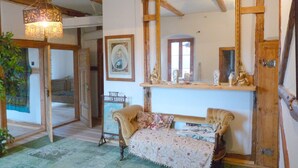 Una habitación con techo de madera, cama con ropa de cama floral, un espejo y una lámpara colgante.