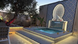 Una piscina con borde de azulejos y una pared decorativa.