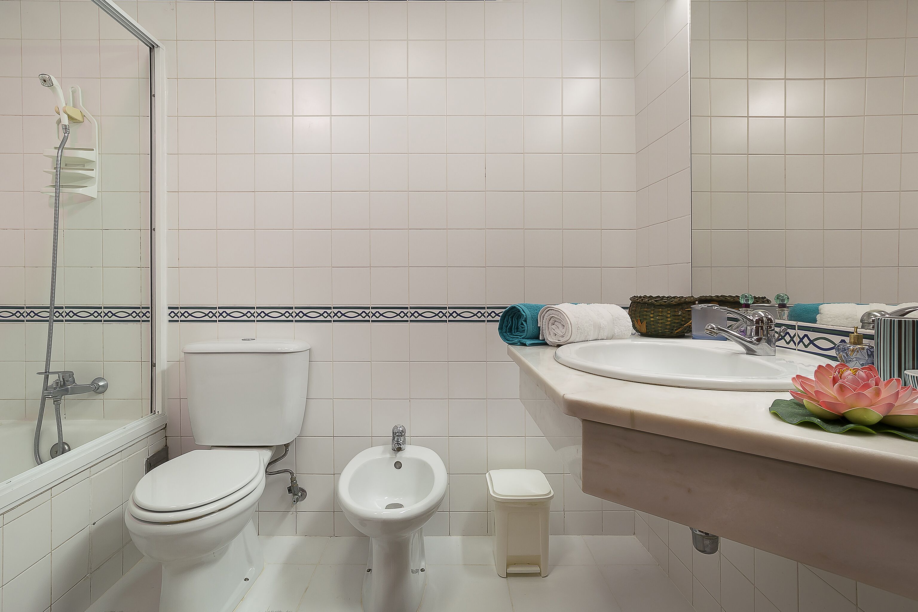 A bathroom with a toilet, bidet, and a sink with a mirror.
