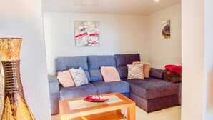 Ein Wohnzimmer mit einem blauen Sofa, einem Holztisch und einer Vase.