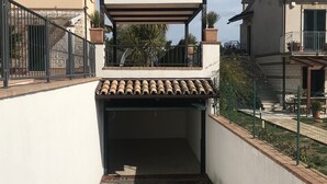 A covered outdoor area with a tiled roof, a brick pathway, and a white wall. - Modern open space tavern, with shared garden use (Numana)