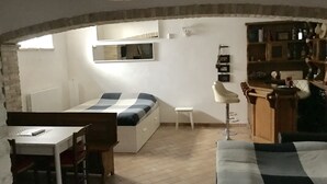 A cozy, compact room with a bed, a small table, a chair, a stool, and a sofa. - Modern open space tavern, with shared garden use (Numana)
