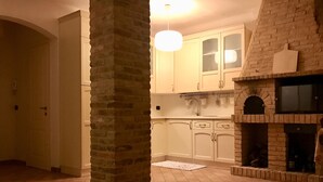 A kitchen with white cabinets, a brick column, a hanging light, and a brick fireplace. - Modern open space tavern, with shared garden use (Numana)