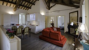 Amplia sala de estar con un sofá rojo, mesa de comedor, sillas y una cocina al fondo.