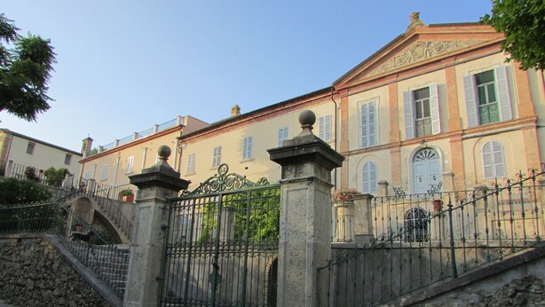 Un edificio histórico con entrada porticada, escalones de piedra y un estilo arquitectónico tradicional.