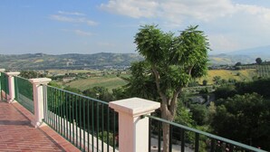 Un balcón con vistas a colinas onduladas y un árbol.