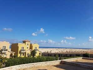 Ein Wohngebiet mit gelben Gebäuden, einer Steinmauer und Blick auf einen Strand.