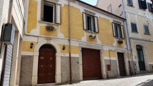Un bâtiment à la façade jaune, doté de deux portes marron et de fenêtres avec des volets.