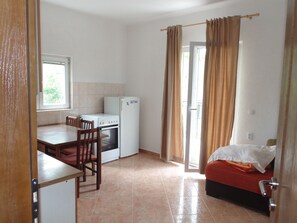 A compact room with a kitchenette, a dining area, and a bed.