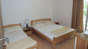 Une chambre avec deux lits simples, une table de chevet avec une lampe et une fenêtre avec des rideaux.