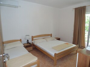A bedroom with two single beds, a bedside table with a lamp, and a window with curtains.