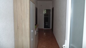 Un couloir étroit, avec une porte en bois sur la gauche et une porte blanche sur la droite.