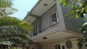 Un bâtiment moderne doté d’un balcon, d’un palmier et d’un appareil de climatisation.