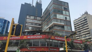 A McDonald's restaurant with a modern glass facade, located in an urban area with tall buildings and a traffic light in the foreground. - Kennedy Park Miraflores apartment (Miraflores)