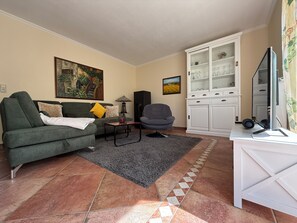 Un salon comprenant un canapé, un fauteuil, une table basse et un meuble.
