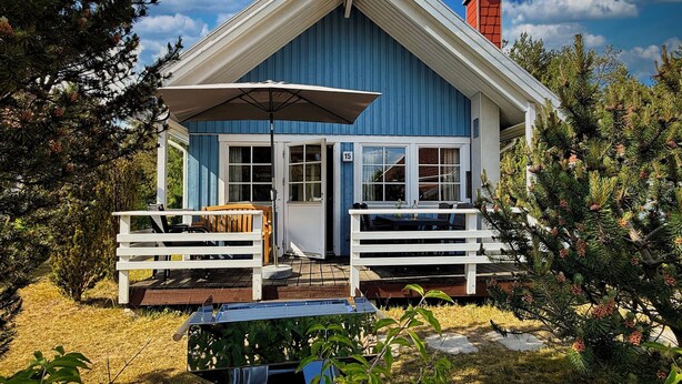 A blue house with a porch, two white benches, and a table with an umbrella. - Holiday house with 3 bedrooms directly on the Useriner See with bathing beach, fireplace (Userin)