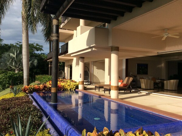 A modern resort with a swimming pool, outdoor seating, and lush landscaping.