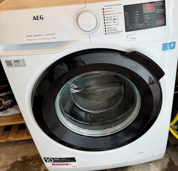 A front view of a white AEG 6000 series washing machine with a digital display and control panel. - Cozy bungalow in rural area near beautiful dunes, beach and sea. (Schoorldam)