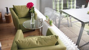 Un espacio moderno de estar con un sofá verde, una mesa de cristal y vistas al exterior.
