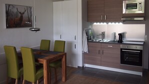 Una cocina moderna con microondas, horno y pileta. Hay una mesa de comedor con sillas y un cuadro en la pared.