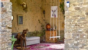 Una habitación rústica con pared de piedra, un caballo balancín de madera, una mesita pequeña y una alfombra colorida.