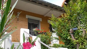 Una casa de madera con fachada blanca, una ventana visible y una escalera.