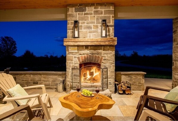 Relax by the outdoor fireplace with a view of the surrounding landscape.