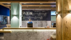 A reception desk with a modern design, featuring a concrete counter and wooden accents. - Ibis Budget Muenchen Airport Erding (Erding)